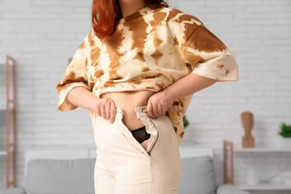 Image of woman trying to do her trousers up after pregnancy weight gain Walsall Wood