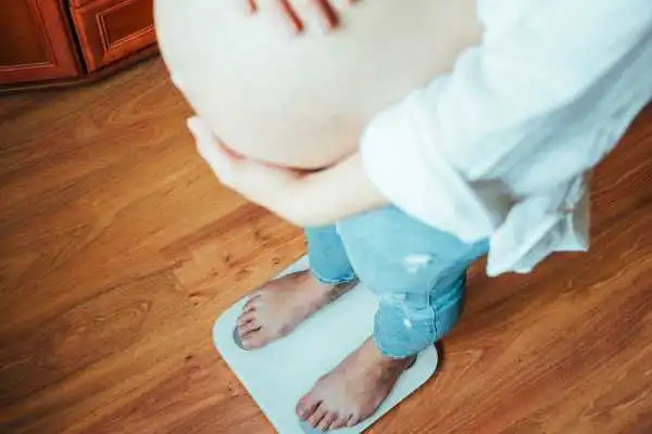 Image of woman weighing herself and experiencing weight gain through pregnancy Walsall Wood